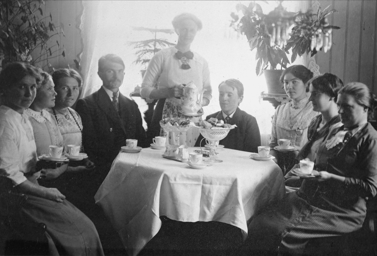 Gruppebilde av syv kvinner og to menn rundt et bord med kaffe og kaker.