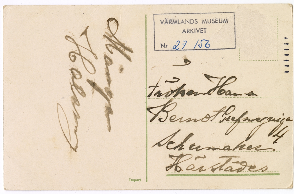 Två barn leker med dockor och matar den ena med sked. Barnen är klädda i klänningar eller koltar i skogsgrönt respektive beige. Båda har spetskragar och den i beige klänning har ett blått midjeband. Barnet i grön klänning har svarta strumpor och ljusbruna kängor med snörning. Samma barn matar en docka i famnen med ägg från en äggkopp på en assiett. Assietten och äggkoppen är vita med blå dekorrand. Ytterligare ett helt ägg ligger på assietten. I bakgrunden står och sitter ytterligare två dockor. Alla tre dockorna är klädda i klänningar med olika modeller och färger; rosa blått och vitt. Någon har midjeband, någon har hätta med snörning under hakan.