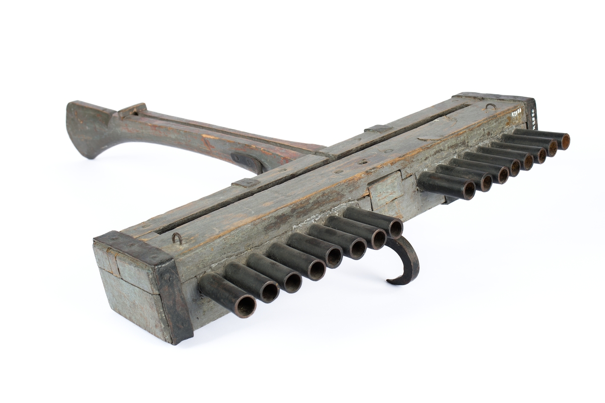 Skottbalk (orgelbössa).  Material: Trä med beslag av järn. Vapnet har 16 stycken pipor av järn. Från 1670-talet.