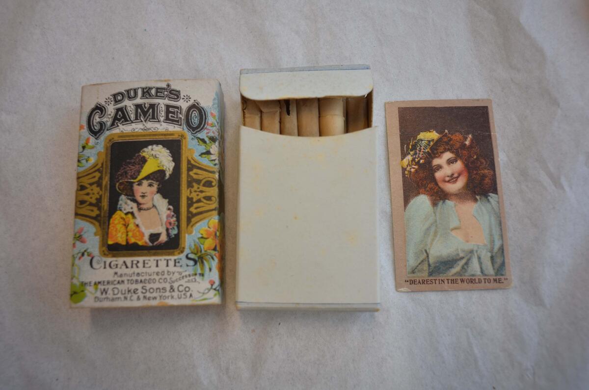 Cigarettpaket, innehållande 12 cigaretter av märket "Duke´s Cameo". Rektangulär vit ask med tryck i svart, guld och gult m.m. På framsidan en kvinnobild inom ram, ovanför vilken står: Duke´s Cameo och under bilden: Cigarettes Manufactured by The American Tobacco Co. Successor To W. Duke sons & Co. Durham. N.C. & New york, U.S.A. På sidorna och baksidan finns bl.a. målningar av blommor.