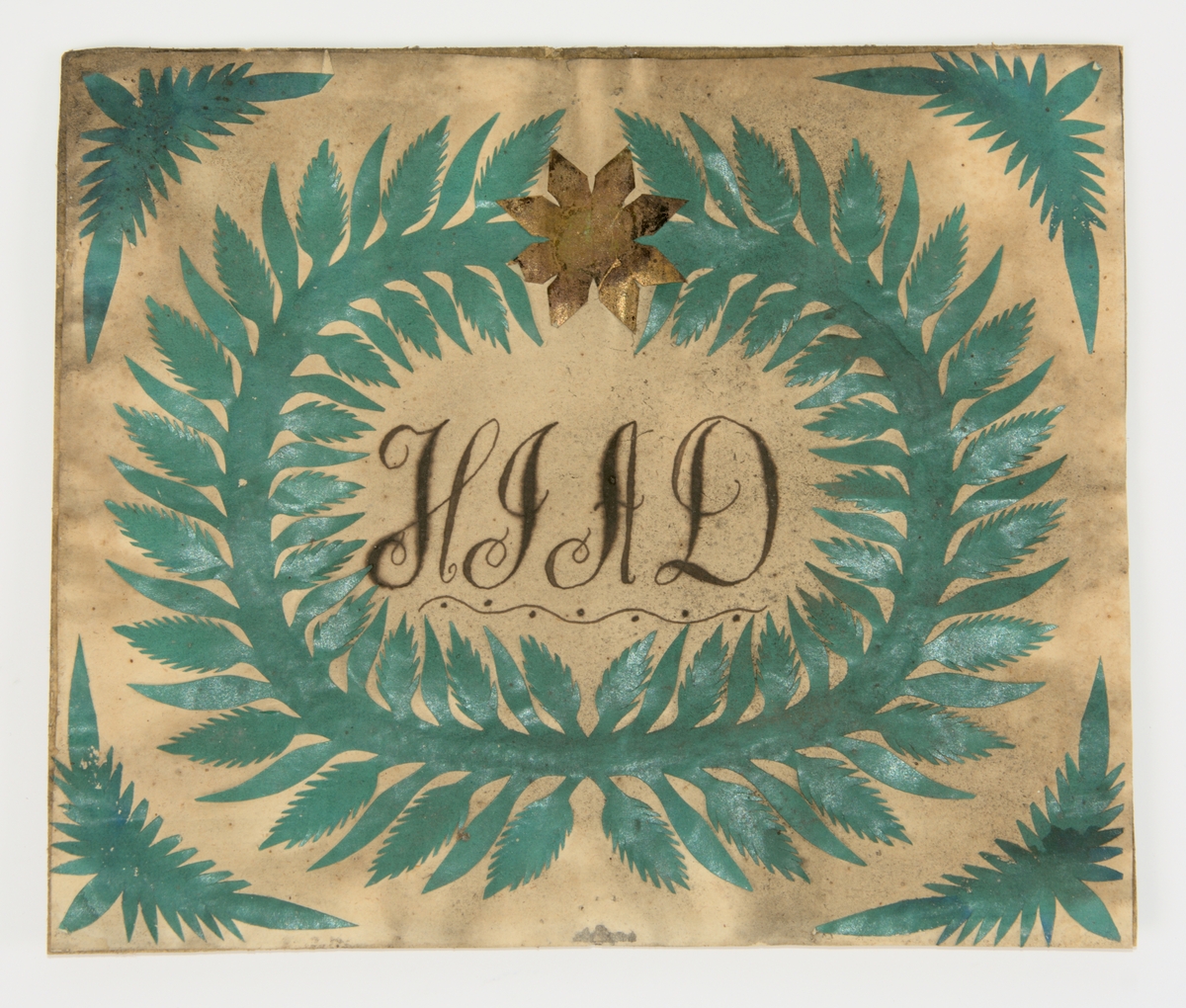 Minnestavla på vitt papper med bladverk av grönt papper som klistrats på. Bladverket är format som en krans med en stjärna i övre delen. Samma typ av bladverk finns i minnestavlans fyra hörn. Inuti kransen finns initialerna H.I.A.D.

På bakstycket finns följande text skriven i blyerts:
Målad av Johannes Karlsson Stamnared som även gjort ramen.