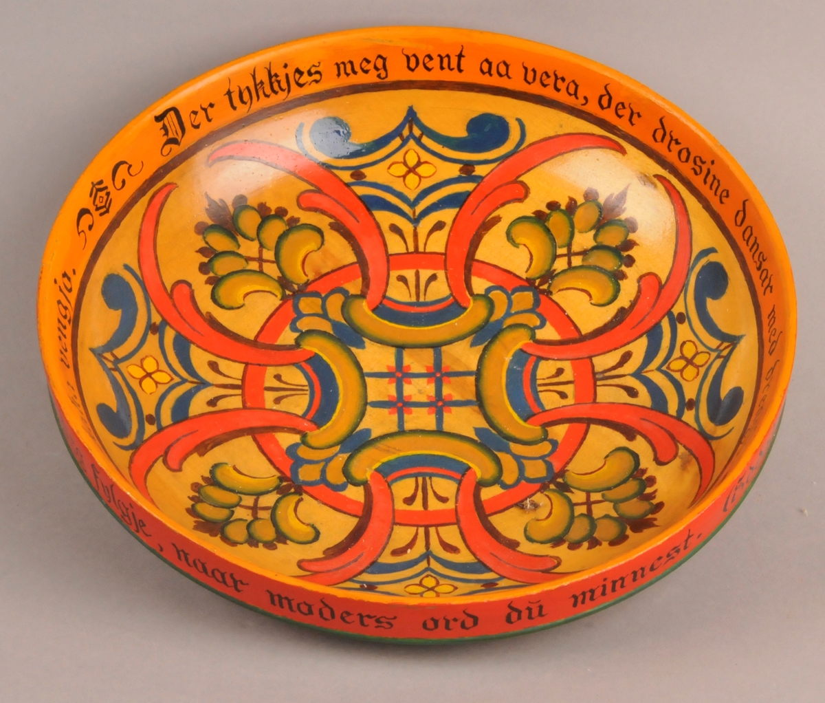 Dreia trebolle med skorne og måla roser på utsida, måla roser og tekst inni bollen.. Tekst skore inn under botn ØV 20-10 1955. Påmåla bollerim på usida av kanten øverts: "Talen til mor di tak du i mot og gjev paa ordi gaum. Daa skal heider og heppe deg fylgje, naar moders ord du minnest. ( Eddakvæde.)" Bollerim inni bollen: "Der tykkjest meg vent aa vera, der drosine dansar med drengjo. Gaukjen gjel i grønan lid, og fuglane skaka venjo."