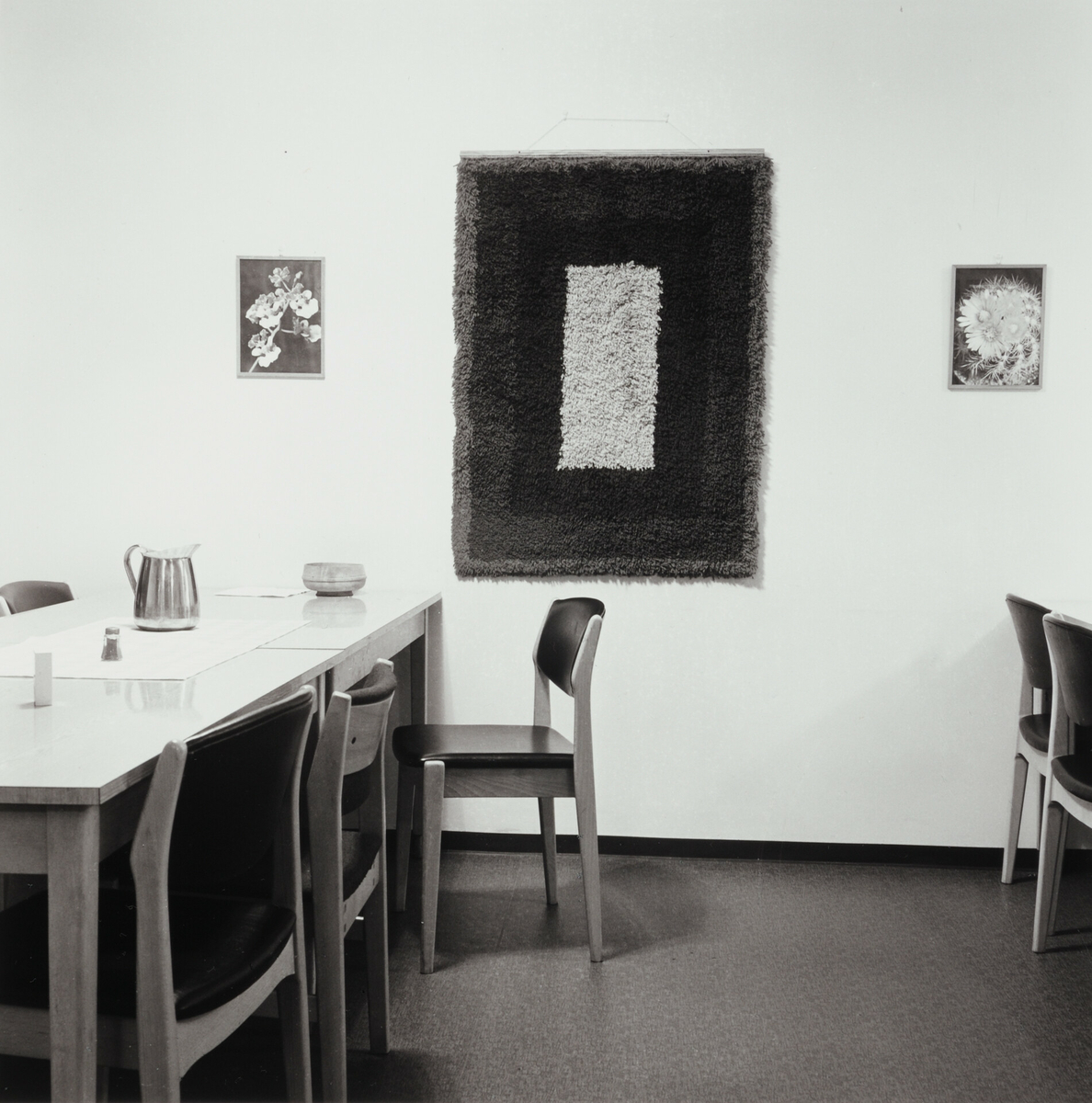 Spisesal med enkel møblering og symmetrisk hengt kunst på veggen.