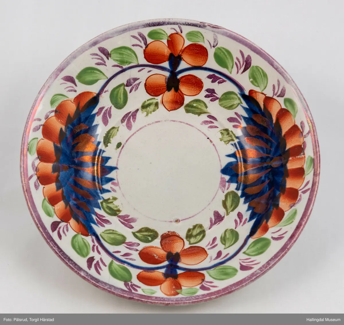 a) Kopp: Stentøy, hvit, liten. Markert fotring. Siden svunget. Utv. polygongal, dekorert med 2 store trekantede blomster i blått og rødt. Mellom dem 6 røde og grønne blad.
b) Skål: Stentøy, hvt, rund. Forholdsvis dyp med skrå side. Samme dekor som koppen. R.B.S.