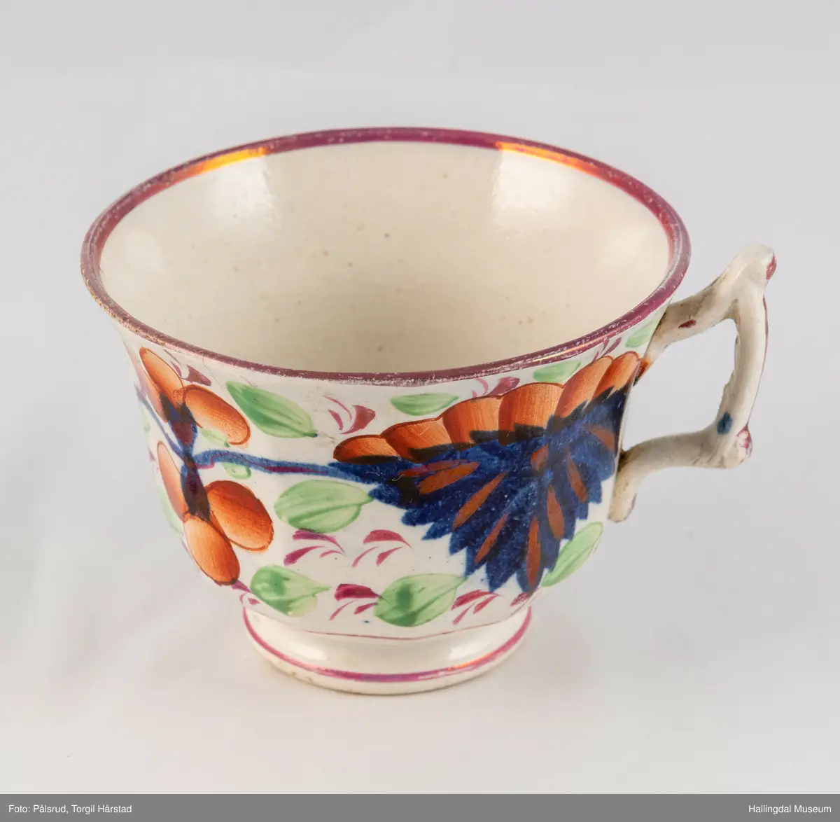 a) Kopp: Stentøy, hvit, liten. Markert fotring. Siden svunget. Utv. polygongal, dekorert med 2 store trekantede blomster i blått og rødt. Mellom dem 6 røde og grønne blad.
b) Skål: Stentøy, hvt, rund. Forholdsvis dyp med skrå side. Samme dekor som koppen. R.B.S.