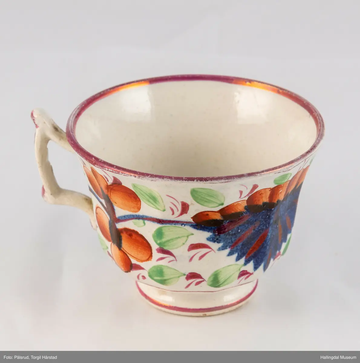 a) Kopp: Stentøy, hvit, liten. Markert fotring. Siden svunget. Utv. polygongal, dekorert med 2 store trekantede blomster i blått og rødt. Mellom dem 6 røde og grønne blad.
b) Skål: Stentøy, hvt, rund. Forholdsvis dyp med skrå side. Samme dekor som koppen. R.B.S.