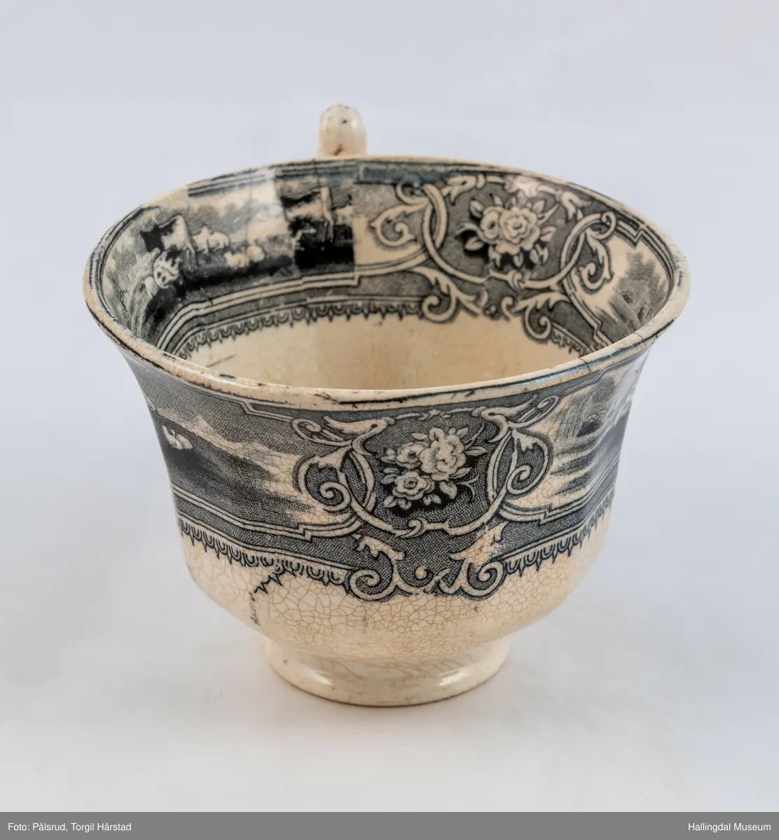 a) Kopp: Stentøy, hvit, liten. Markert fotring. Siden svunget. Utv. polygongal, trykte sorte dekorasjoner. I bunnen innv. landskap. langs randen innv. og utv. 2 blomsterornamenter og 2 felt med kuer og sauer i et slettelandskap. Sprukket.
b) Skål: Stentøy, hvt, rund. Forholdsvis dyp med skrå side. Siden samme dekor som koppen. I bunnen landskap med trær, vindmølle, rytter og kyr. Sprukket og limt. R.B.S.