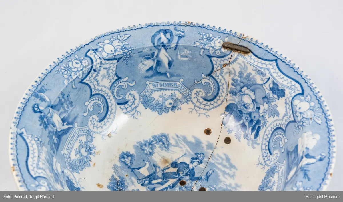 Flint? Hvitt, rundt, fotring. Utbuket side. markert kant med blå dekorasjoner. I bunnen landskap med jeger, symboliserende "april". Veggen innv. og utv. - blomsterklaser omgitt av knekkete bånd, mellom dem kvinnefigurer. Sprukket og klinket. Et stykke mangler. Bunnen stemplet: "Patterson" 12.

R.B.S.