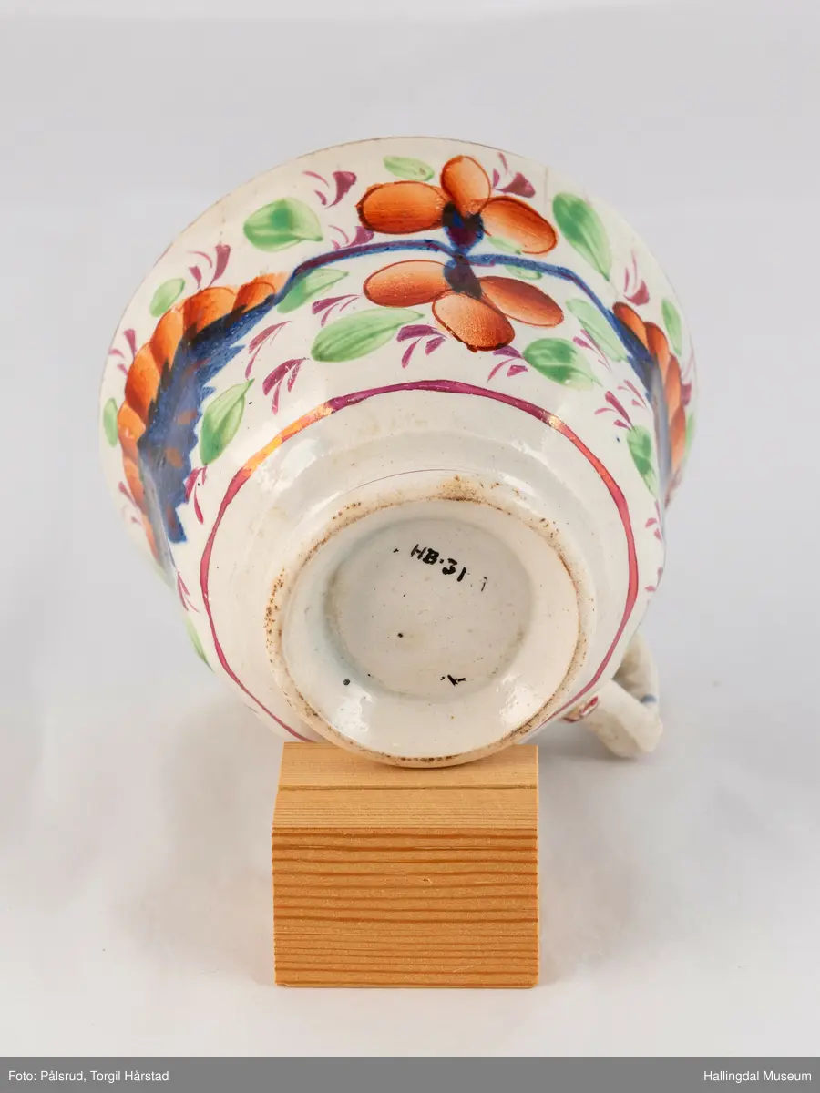 a) Kopp: Stentøy, hvit, liten. Markert fotring. Siden svunget. Utv. polygongal, dekorert med 2 store trekantede blomster i blått og rødt. Mellom dem 6 røde og grønne blad.
b) Skål: Stentøy, hvt, rund. Forholdsvis dyp med skrå side. Samme dekor som koppen. R.B.S.