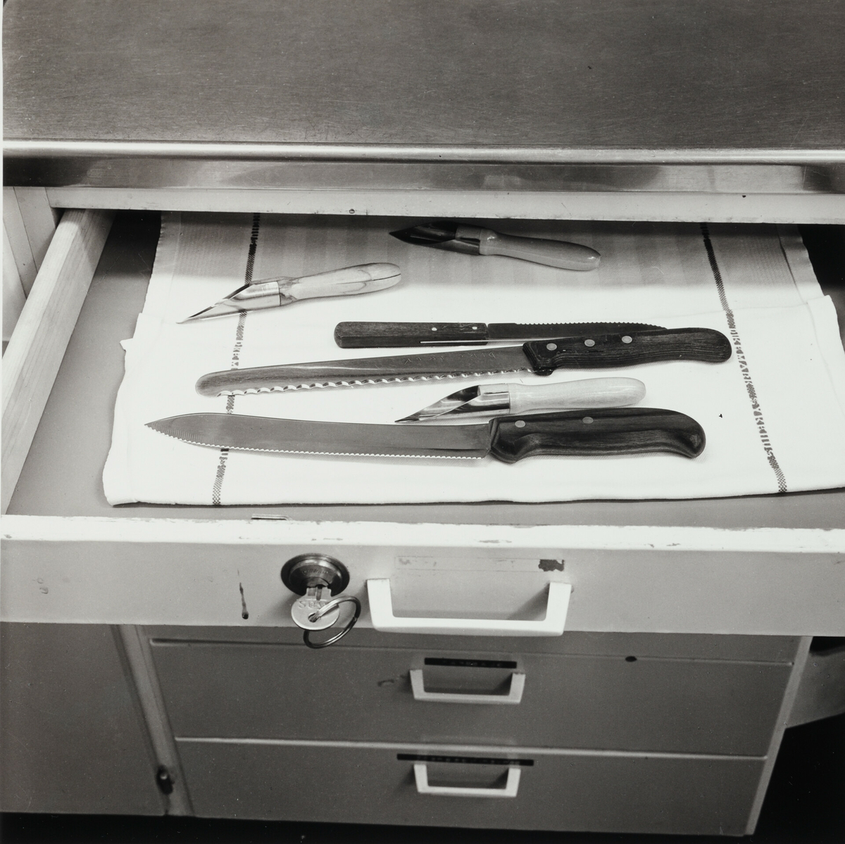 Åpen skuff med kniver og potetskrellere. Skuffen er låsbar og nøkkelen henger i låsen.