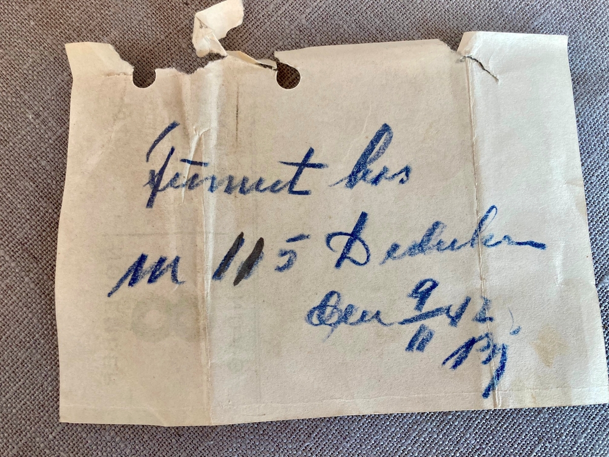 En rund metalleske med hengslet lokk. Ligner en snusdåse. Boksen inneholder noe rusk, trolig tobakk, samt ubestemmelig materiale som ligner rester av sort tekstil, samt små runde rund "knapp" i metall som har tagger rundt kanten.