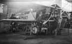 Interiör av Flygkompaniets verkstäder på Malmen vid motorservice på flygplan Fokker D, VII nr 937. Två män i arbete, omkring 1920-1925.