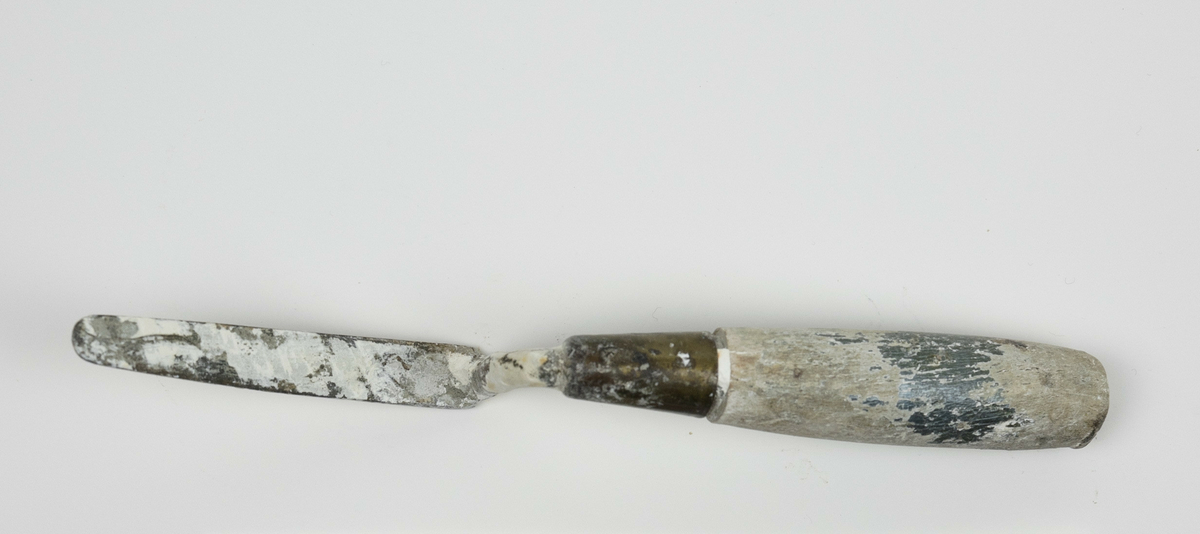 Spatel brukt av Nils Aas til modellering. Den består av et stykke metall formet til en flat, oval form i enden av et trehåndtak. Hele verktøyet er fullt av rester etter gips. Håndtaket var opprinnelig grønt, mesteparten av malingen har derimot flasset av. 