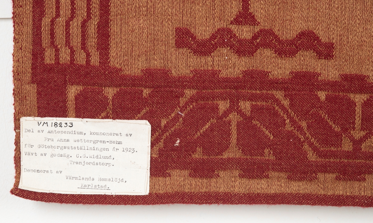 Antependium (del av) i lin och ylle. Röd botten med mönster i djur- och växtmotiv i gult. Mönsterbård runtom. Lin i varp, ylle i inslag. Teknik: "Satinbindn damast".