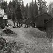 Mellan några timrade hus i Trolldalen vilar de som slutfört en orienteringstävling i Växbo den 26 maj 1957.
