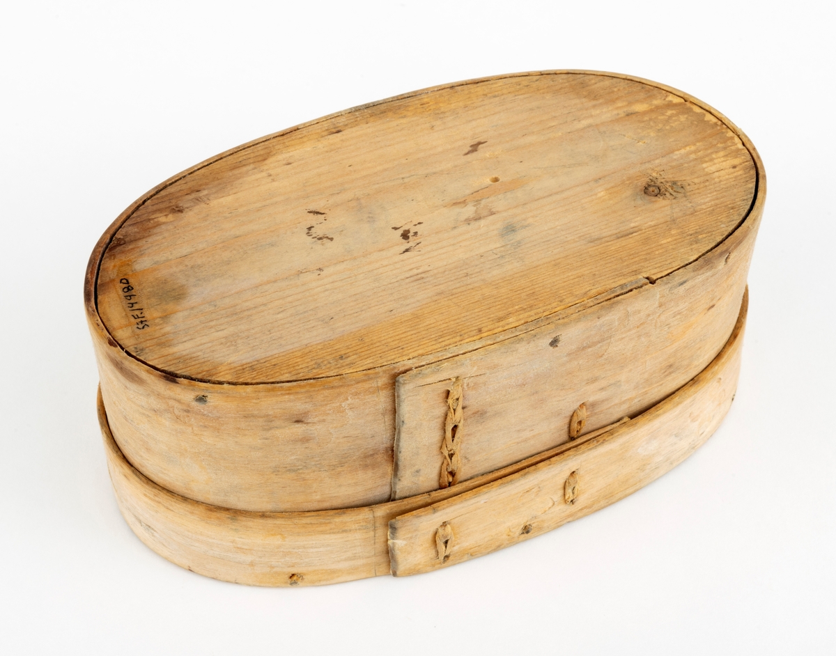 Øskje - en oval beholder med lokk, utført i såkalt sveipeteknikk. Botnplata er et ovalt granbord - 15,1 X 8,0 centimeter. Utenpå denne er det festet sidevegger, lagd av ei cirka 5,5 centimeter bred og 2,6 millimeter tjukk bjørkeplate som antakelig har vært godt fuktet før den ble «brettet» rundt en oval mal og tørket der. Seinere har man beholdt formen ved hjelp av to vertikale sømmer av bjørketeger der hvor ytterendene på veggskia overlapper hverandre. Lokket er lagd på samme måte. Her er plata 15,4 centimeter lang og 8,2 centimeter bred. Rundt denne er det festet en ytterkant, lagd av ei 2,6 centimeter bred og bortimot 2 millimeter tjukk bjørkeskie. Også her er det to vertikale tegersømmer der hvor endene av emnet overlapper hverandre. Sideveggene, både på sjølve beholderen og på lokket, er festet til de ovale granplatene de omslutter ved hjelp av tynne treplugger. Lokket er såpass stort at det omslutter overkanten på beholderen. Oversida av lokket og ytterveggene på sidene er påstemplet dekorelementer ved hjelp av svijern. Innvendig bærer treet preg av å ha vært i nærkontakt med en substans som har vært rik på fettstoffer - muligens skjørost eller pultost.