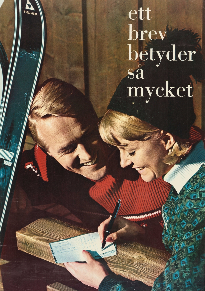 Man och kvinna skriver brev tillsammans. Mannen håller i ett par skidor. Kvinnan har en mössa.