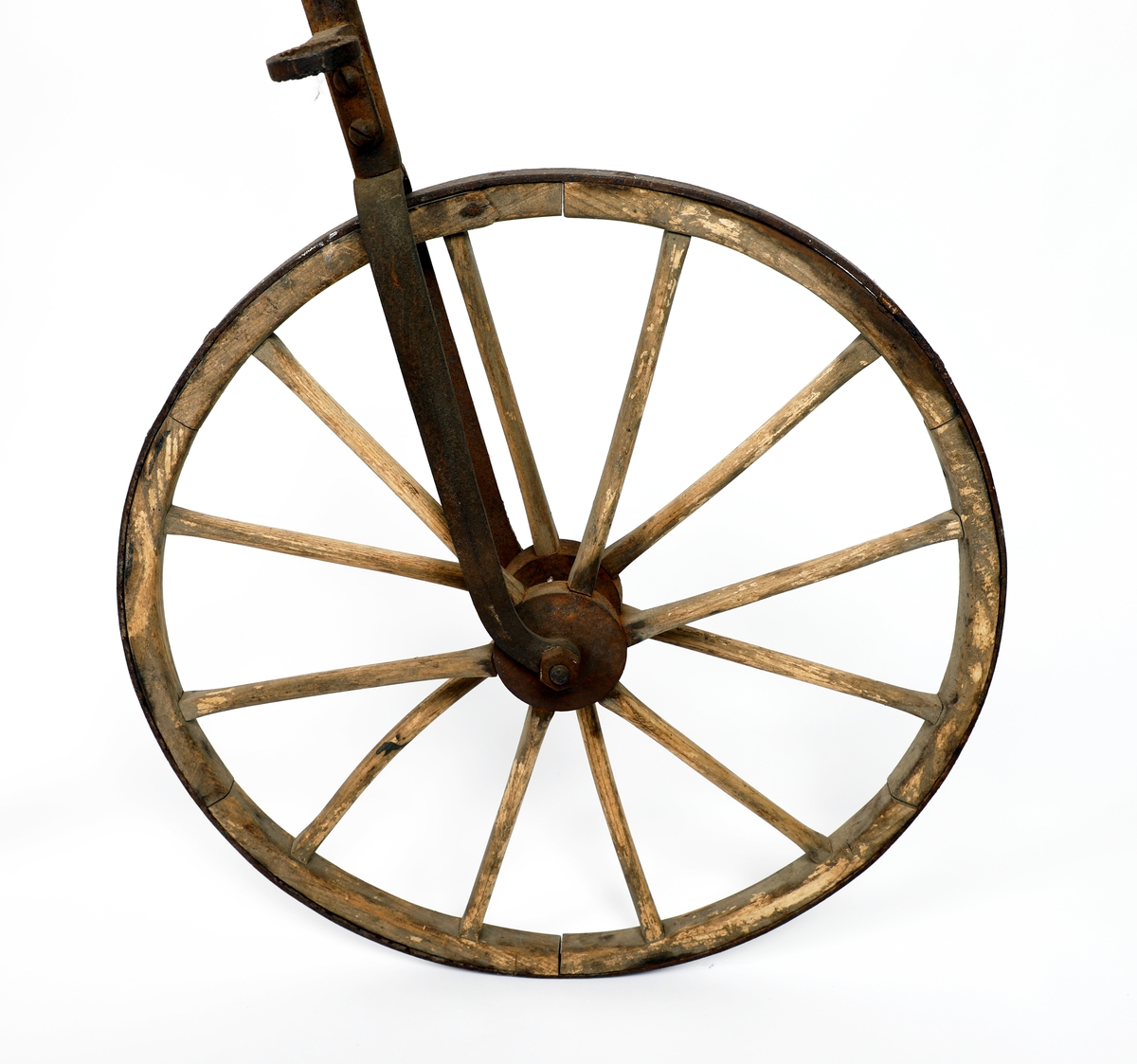 Veltepetter i med hjul av tre og stang av metall. Justerbart sete og pedaler. Sete trukket i lær. Styreholker av tre.