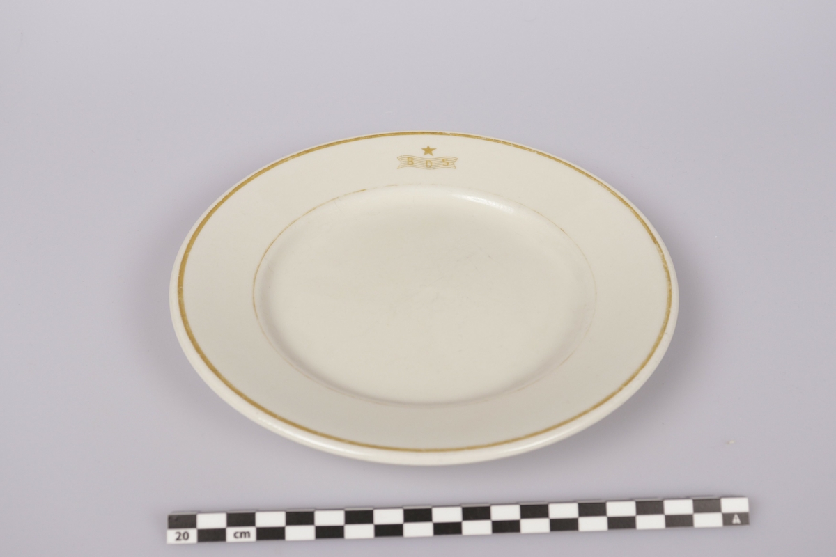 3mm gullfarget stripe langs ytterkant. Rederiflagget til Det Bergenske Dampskibselskab er trykt på kanten av asjetten. På indrekanten er trykt en 1mm gullfarget stripe, som har blitt svak på noen steder. 