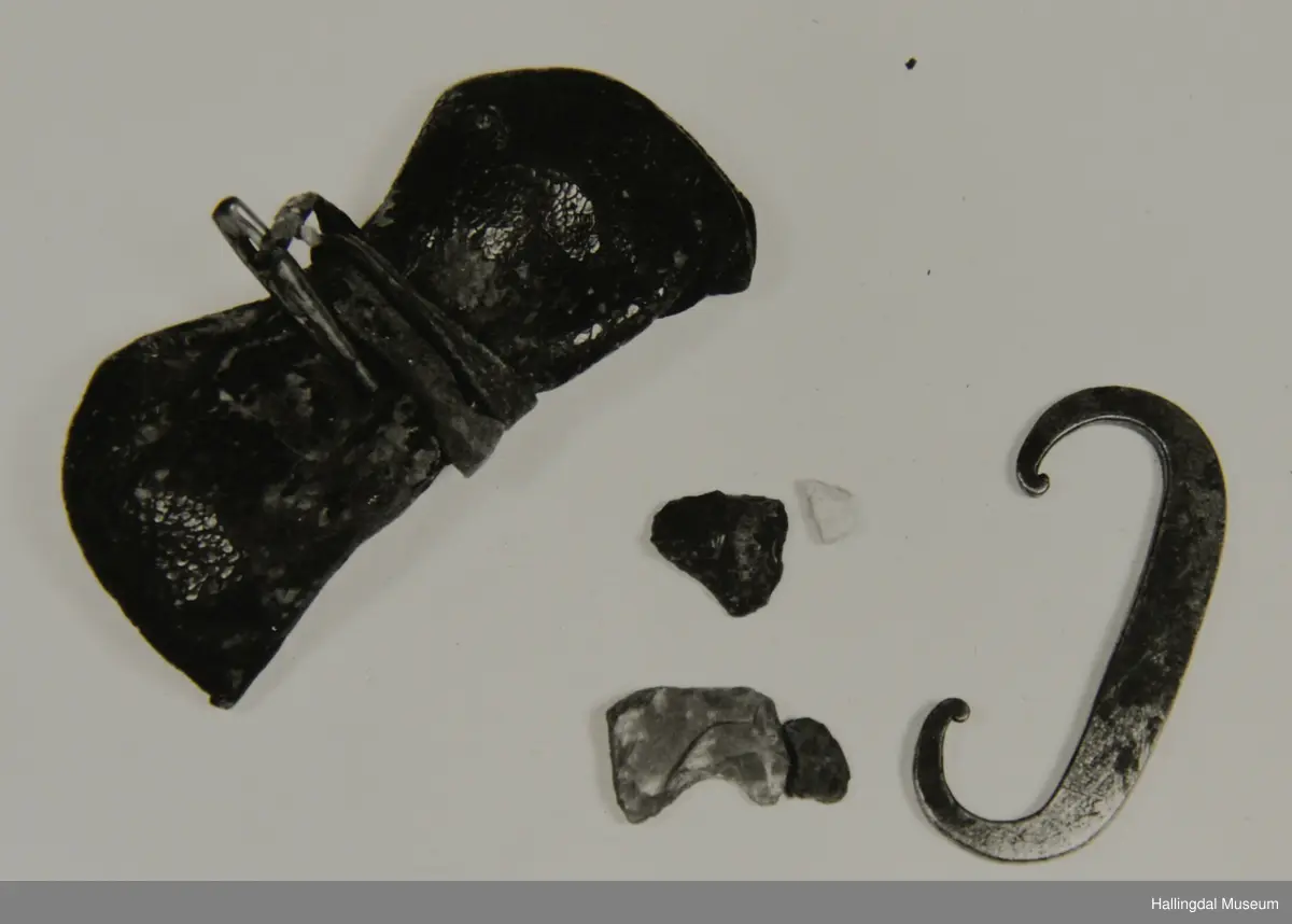 A. Pung. Sydd av eit lærstykke, sydd saman i sidene med tråd, ,lærstykketb er tredobbelt når pungen er attleten. I loket er det sydd fast ei lærreim til å surre rundt pungen. I enden av reima er det festa ei lita trenål, spikka av bjørk.
B. Ildjarn. Smidd av eit jarnstykke, bogeforma, breidast og tjukkast på midten, rektangulært tverrsnitt, smaqlnar av i båe endane og ørlite opprulla ytst i kvar ende.
C. og D. 2 små flintbitar, svært ujamn form.