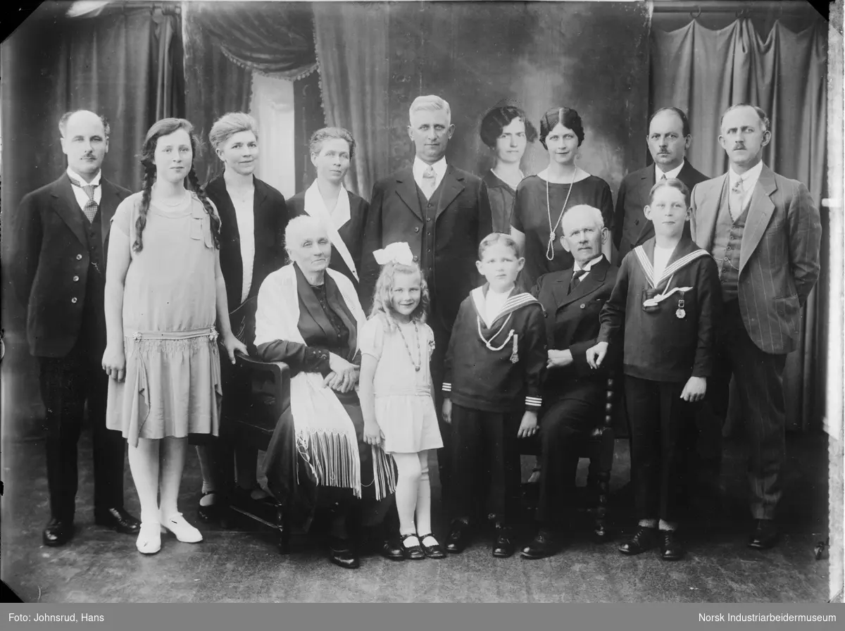 Gruppeportrett av storfamilie. Flere voksne og barn samlet for fotografering i studio.