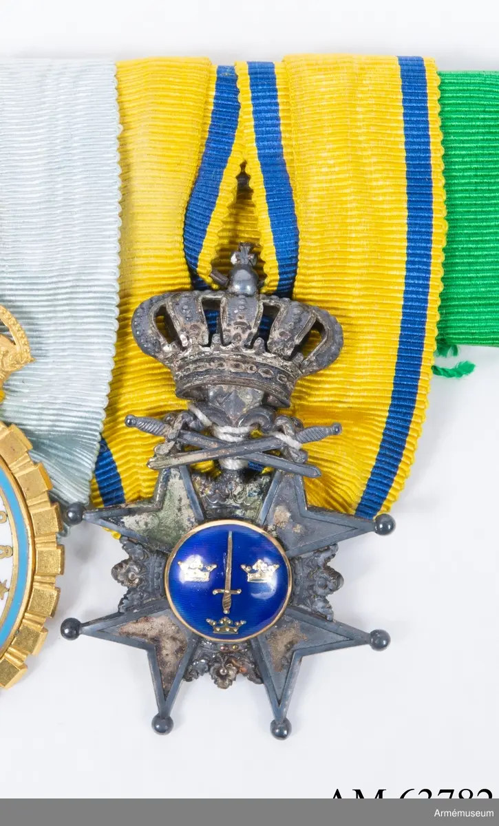 Grupp M II.
Ett snedställt johannitkors av silver med åtta uddar slutande i kulor, mellan korsets armar kronor och på dess översta armar två korslagda svärd med uppåt, allt i silver. I mitten av korset en rund, av en smal guldkant omgiven glob av blå emalj, som har ett upprättstående svärd och Sveriges tre kronor av guld. Globen består på frånsidan av silver och innehåller i relief devisen: "PRO PATRIA" samt ett upprättstående svärd, vars spets omgives av en lagerkrans. Ovan korset en kunglig krona av silver. Medaljband gult med mörkblå kanter. Bandets bredd 35 mm.

Sitter ihop med Jubileumstecken och ett grönt medaljband.