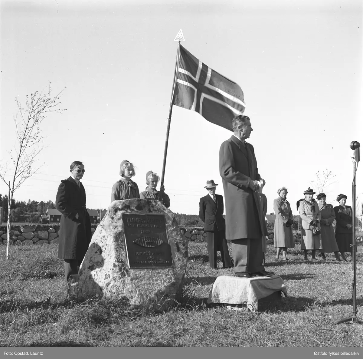 Avduking av minnestein for Tune-skipet (utgravd i 1867), på funnstedet Nedre Haugen gård, Rolvsøy, 14. september 1947. Minnestenen ble reist av Østfold Historielag. Formannen Bjarne Didriksen foretok avdukingen og talte.
87-år gamle Mathilde Haugen var blant hedersgjestene,  hun så utgravingen i 1867 og hadde nå påvist funnstedet. Syver Haugen og kona sørget for gjestene med bevertning på gården Haugen. Videre deltok ordfører i Rolvsøy Hans Kristiansen som også talte.
Helt til venstre:  antakelig konservator Sverre Marstrander ved Universitetes Oldssaksamling.