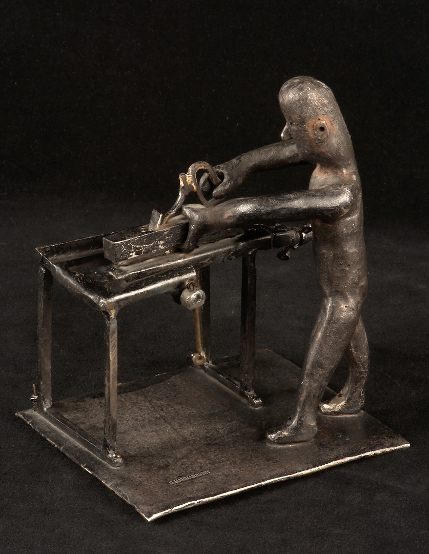 Skulptur i gjutjärn föreställande en man vid en hyvelbänk.