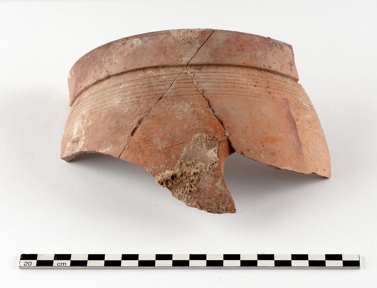 Samling bestående av sex fragment av invändigt glaserat yngre rödgods, gulbrun-mörkbrun glasyrfärg. Tre till fyra kärl, två grytor och en skål kan identifieras. Datering: 1650-1720. Några skärvor ihopklistrade utifrån passning.