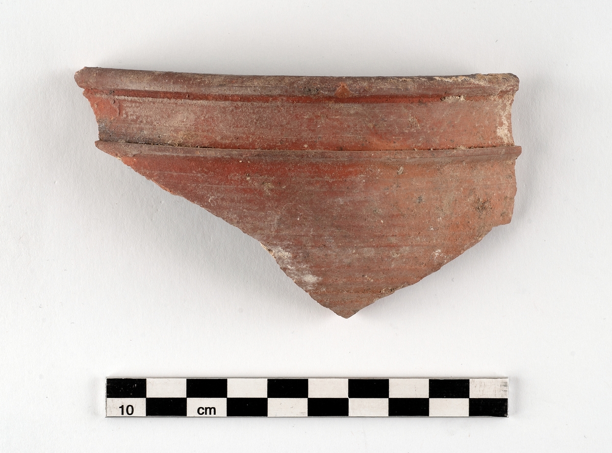 Samling bestående av sex fragment av invändigt glaserat yngre rödgods, gulbrun-mörkbrun glasyrfärg. Tre till fyra kärl, två grytor och en skål kan identifieras. Datering: 1650-1720. Några skärvor ihopklistrade utifrån passning.