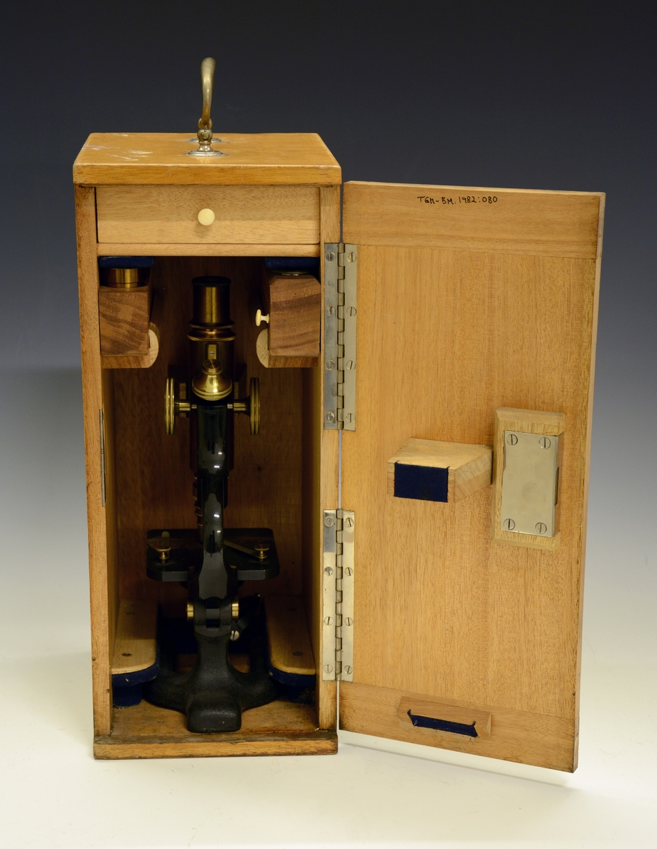 Mikroskop i kasse. Fra protokollen: Kassen av tre, lakkert, med dør. Ekstralinser og en skuff i kassen. Mikroskopet av sortlakkert metall og messing. Påtrykt "Seibert in Wetzlar 15453"