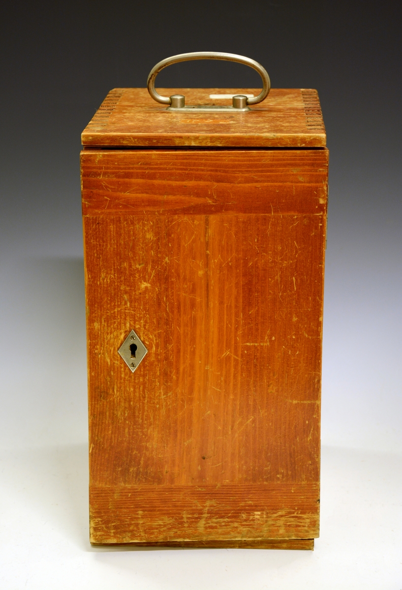 Mikroskop i kasse. Fra protokollen: Mikroskop. Stativet av massivt metall med hesteskoformet fot. Øverst på stativet røret (tubus) med objektiv og okular. Røret reguleres opp og ned ved drev og tannstang (grov innstilling). Bak røret skruehode for fin-innstilling. Mikroskopet har revolver med 4 forskjellige objektiver. Under disse bordet, som er en dreibar sirkulær skive med hull i midten hvorigjennom det sendes lys gjennom objektet fra et belysningsapparat under bordet. Nederst et dreielig plan- og hulspeil, over dette er blender som reguleres med tannstang og drev. Over blenderen kondensor med linser. På ryggen av stativet er inngravert: "No 1856 R. Winkel Göttingen 1891". Mikroskopet er plassert i et treskap med sidehengslet dør som har lås (nøkkelen mangler) og metallhandtak på toppstykket. Inni skapet og på innsiden av døren profilerte treknotter foret med filt, som holder mikrioskopet på plass. Profilerte lister (skinner) bærer et penalhus av tre med skyvelokk, en foret og trukket tre-eske som har et toppstykke med 5 hull (Esken er merket "E. Leitz, Wetzlar") og øverst en treplate med 3 større og 2 mindre hull. På toppen av døren mrk. "132986". Løst inni skapet en kondensor og en metallhylse.