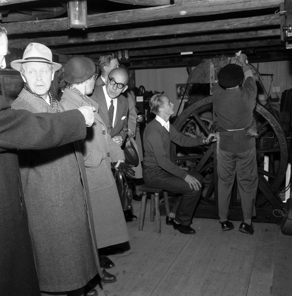Bildserie från invigningen av Wahlbecks repslagerimuseum i Gamla Linköping 1959. Kontorsbyggnaden uppfördes på 1860-talet av byggmästaren Jonas Jonson som hamnkontor och var placerad vid Linköpings hamn. Byggnaden inköptes 1877 av repslagaremästaren Adolf Fredrik Wahlbeck, som lät flytta den till firmans repslageri vid Kanberget där den nyttjades som kontor, butik och magasin. När Wahlbeck 1913 flyttade sin verksamhet till området söder om kyrkogården flyttades även denna byggnad för att 1944 inredas till museum. År 1957 flyttades såväl byggnaden som museet till Gamla Linköping. På bilderna ses bland andra bröderna Gotthard och Ebbe Wahlbeck och den förstnämndes son Olle Wahlbeck.