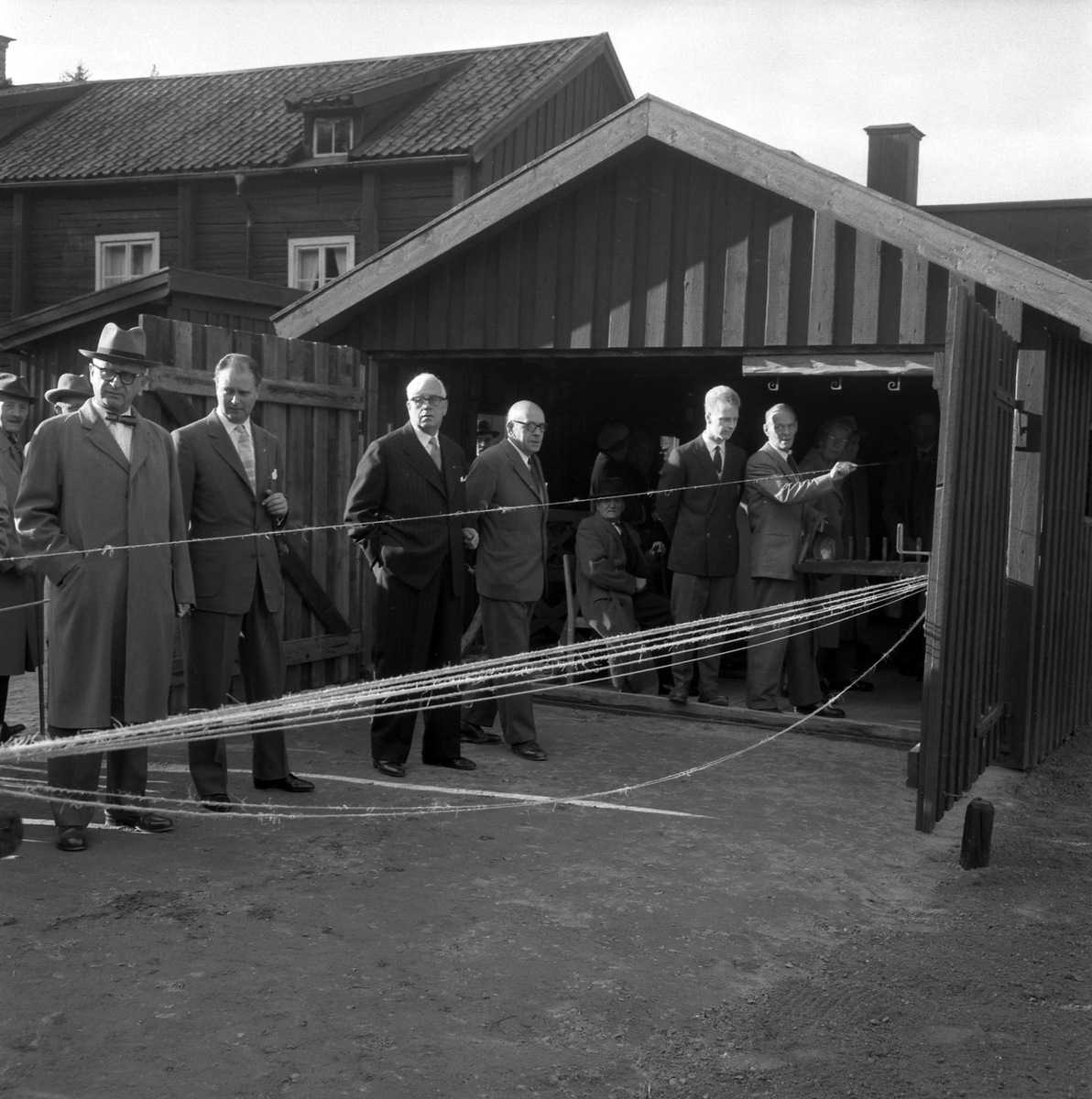 Bildserie från invigningen av Wahlbecks repslagerimuseum i Gamla Linköping 1959. Kontorsbyggnaden uppfördes på 1860-talet av byggmästaren Jonas Jonson som hamnkontor och var placerad vid Linköpings hamn. Byggnaden inköptes 1877 av repslagaremästaren Adolf Fredrik Wahlbeck, som lät flytta den till firmans repslageri vid Kanberget där den nyttjades som kontor, butik och magasin. När Wahlbeck 1913 flyttade sin verksamhet till området söder om kyrkogården flyttades även denna byggnad för att 1944 inredas till museum. År 1957 flyttades såväl byggnaden som museet till Gamla Linköping. På bilderna ses bland andra bröderna Gotthard och Ebbe Wahlbeck och den förstnämndes son Olle Wahlbeck.