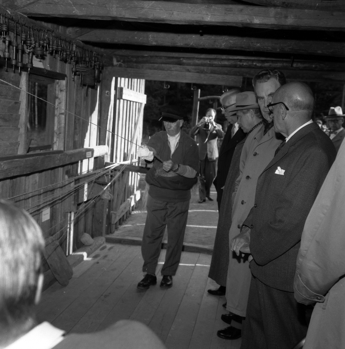 Bildserie från invigningen av Wahlbecks repslagerimuseum i Gamla Linköping 1959. Kontorsbyggnaden uppfördes på 1860-talet av byggmästaren Jonas Jonson som hamnkontor och var placerad vid Linköpings hamn. Byggnaden inköptes 1877 av repslagaremästaren Adolf Fredrik Wahlbeck, som lät flytta den till firmans repslageri vid Kanberget där den nyttjades som kontor, butik och magasin. När Wahlbeck 1913 flyttade sin verksamhet till området söder om kyrkogården flyttades även denna byggnad för att 1944 inredas till museum. År 1957 flyttades såväl byggnaden som museet till Gamla Linköping. På bilderna ses bland andra bröderna Gotthard och Ebbe Wahlbeck och den förstnämndes son Olle Wahlbeck.