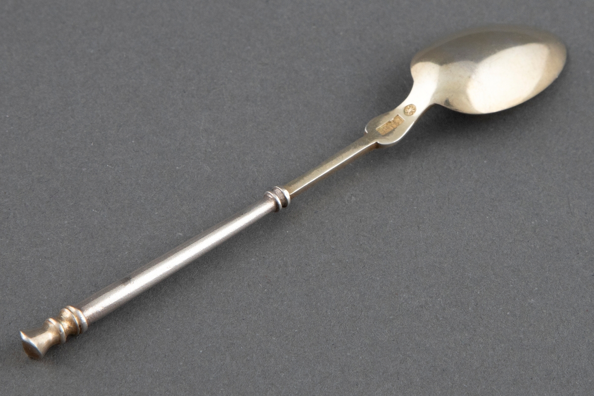 En av seks like teskjeer. Skjeene har dype skjeblad med tilspisset eggform. Bred, profilert ansats til skaftet som er oppdelt i et firkantet og et rundt parti. Øverst ser skafet avsluttet med profilert, skråttavskåret knapp. Skjebladene er forgyllede, noen delvis avslitt.
