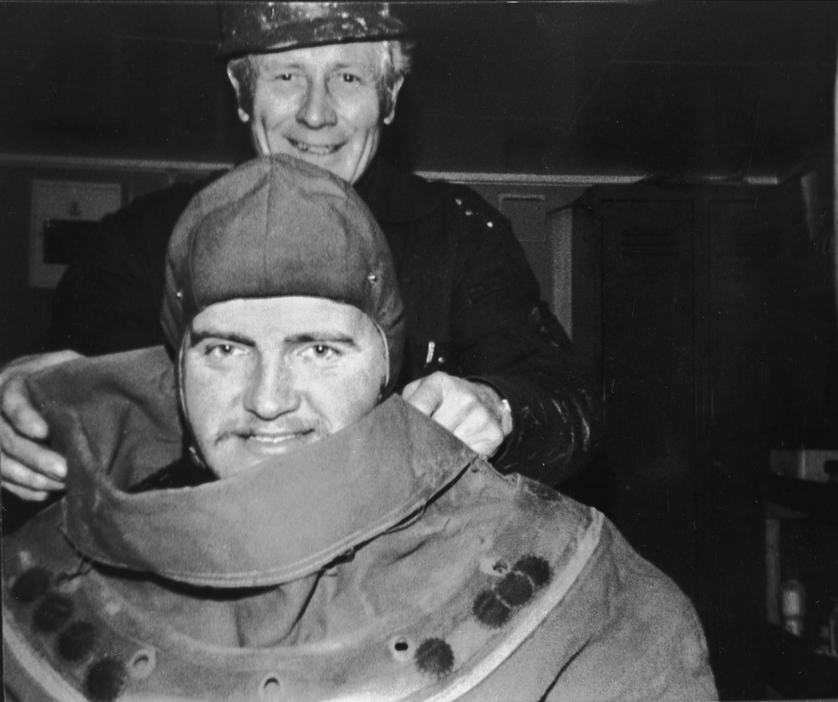 Dykker hjelpes på med dykkerdrakt.