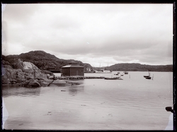 Småbåtar i hamn. I centrum ett fyrkantigt hus.
Nösund.