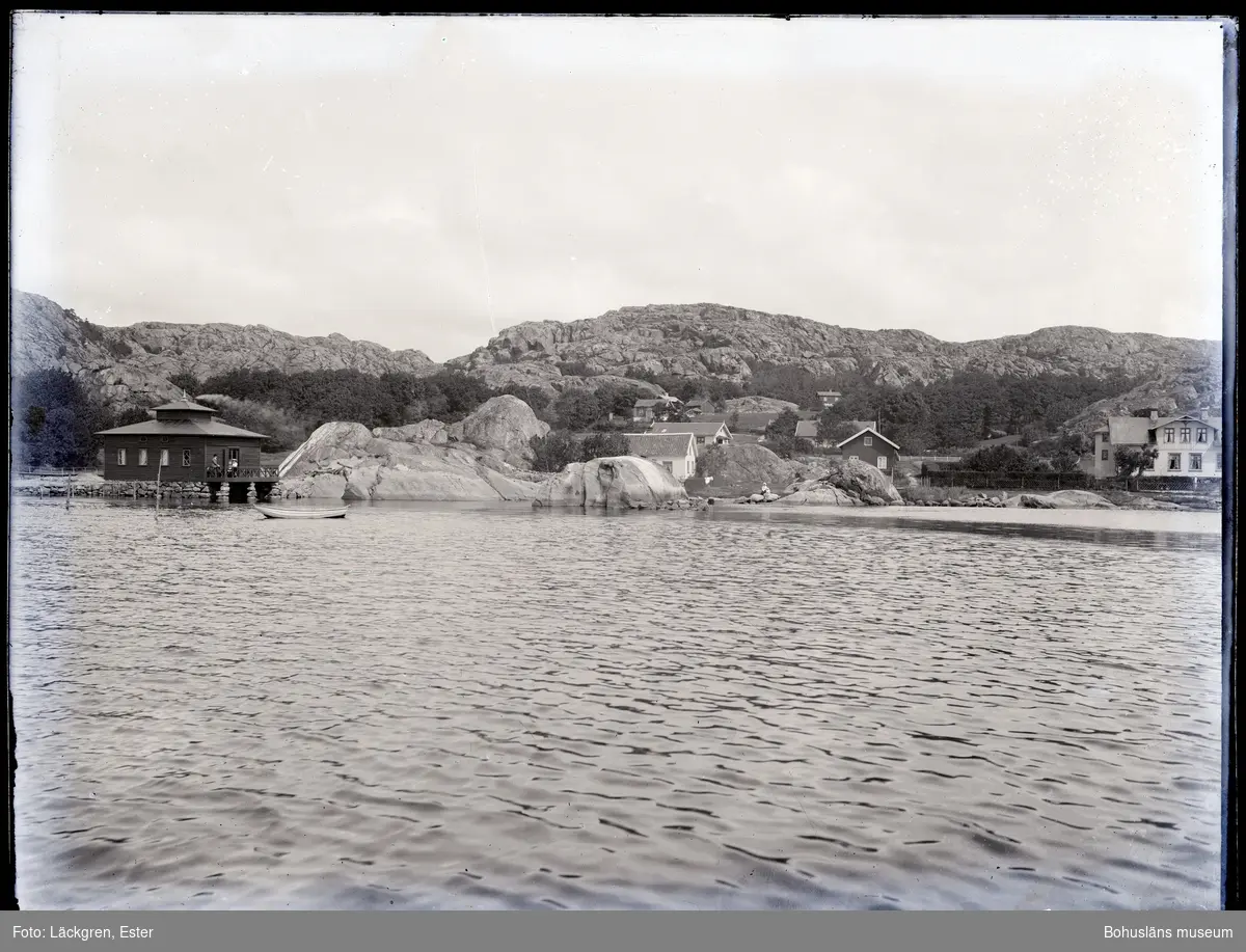Fyrkantigt hus till vänster i bild. Hus på klippor till höger.
Nösund.