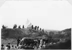 Ett tyg ligger över en skulptur som står på en bergknalle - Kråkberget -  strax söder om Gränna. Folksamling runt omkring. Det är dags för avtäckning av skulpturen 