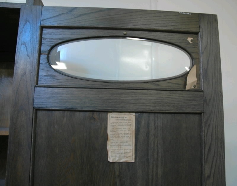 Linneskåp, "äpplet". Jugendstil. Mörkbetsad ek. Delvis fanerad. Svängt överstycke. Lös dörr med ett ovalt glasfönster överst, på baksidan sitter ett papperstryck fastklistrat, motiv blomsterflickor. Mitt på dörren en utskärning i form av två äpplen och fem blad. Mässingsbeslag. Underst en låda med metallbeslag. På insidan av dörren fastklistrad lapp: "Råd vid tvättning av konstsilkeduktyger...". Höjd 193 cm, bredd 71 cm, djup 45 cm, dörrens höjd 140 cm, dörrens bredd 66 cm, dörrens tjocklek 2,5 cm.