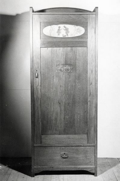 Linneskåp, "äpplet". Jugendstil. Mörkbetsad ek. Delvis fanerad. Svängt överstycke. Lös dörr med ett ovalt glasfönster överst, på baksidan sitter ett papperstryck fastklistrat, motiv blomsterflickor. Mitt på dörren en utskärning i form av två äpplen och fem blad. Mässingsbeslag. Underst en låda med metallbeslag. På insidan av dörren fastklistrad lapp: "Råd vid tvättning av konstsilkeduktyger...". Höjd 193 cm, bredd 71 cm, djup 45 cm, dörrens höjd 140 cm, dörrens bredd 66 cm, dörrens tjocklek 2,5 cm.