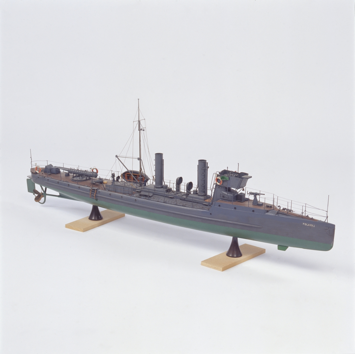 Modell föreställande torpedbåten Polaris. Skrov av trä,  gråmålad,  grön botten. Försedd med urverk som driver propellern. Uppdragning av verket genom aktra skorstenen.