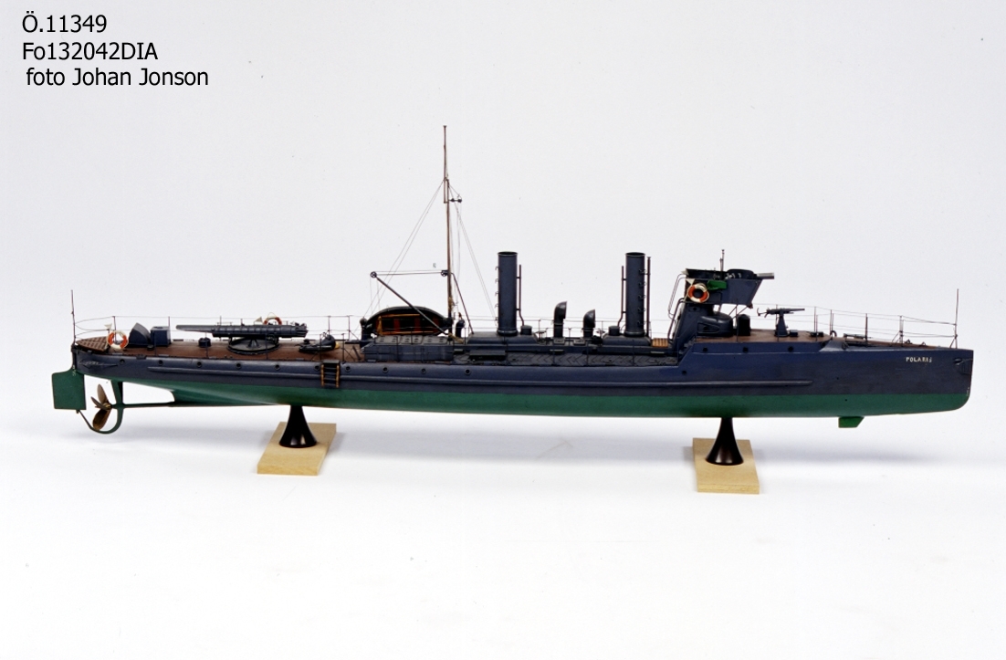 Modell föreställande torpedbåten Polaris. Skrov av trä,  gråmålad,  grön botten. Försedd med urverk som driver propellern. Uppdragning av verket genom aktra skorstenen.