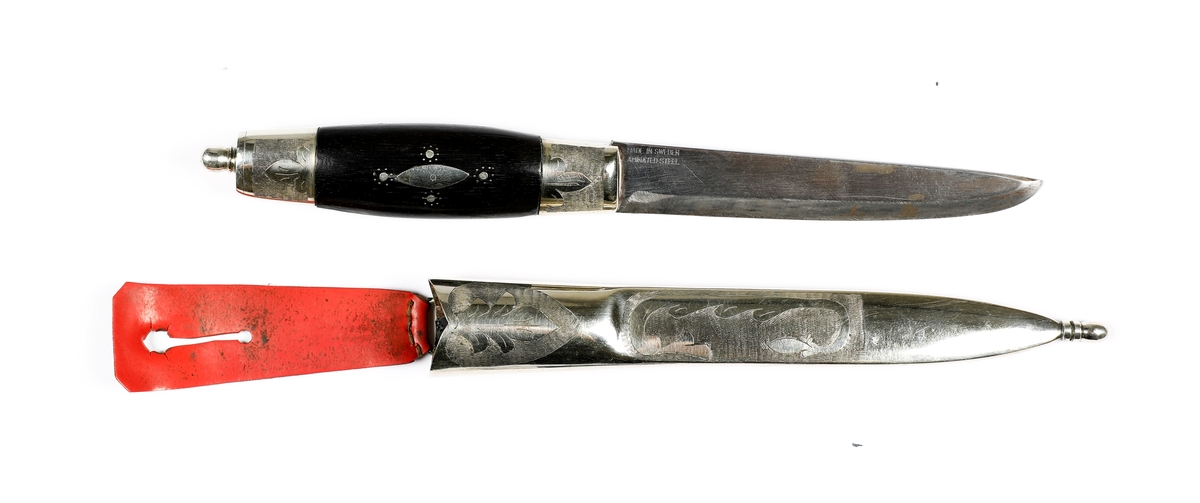 Kniv med slire i nysølv. 

Skaft med holker i nysølv. Endekule i nysølv. Skaft i ibenholt med innfelt dekor i nysølv.  Trambuleringsdekor på endeholker.  
Trambuleringsdekor på slire ( i skaftet).  Slire med  endeholker i nysølv, dekorert med trambuleringer. 
Hengslet hempe i kunstlær.
Bakside av slire påført teksten: H..H 
På knivskaftet står det: Made in Sweden. Laminated steel.