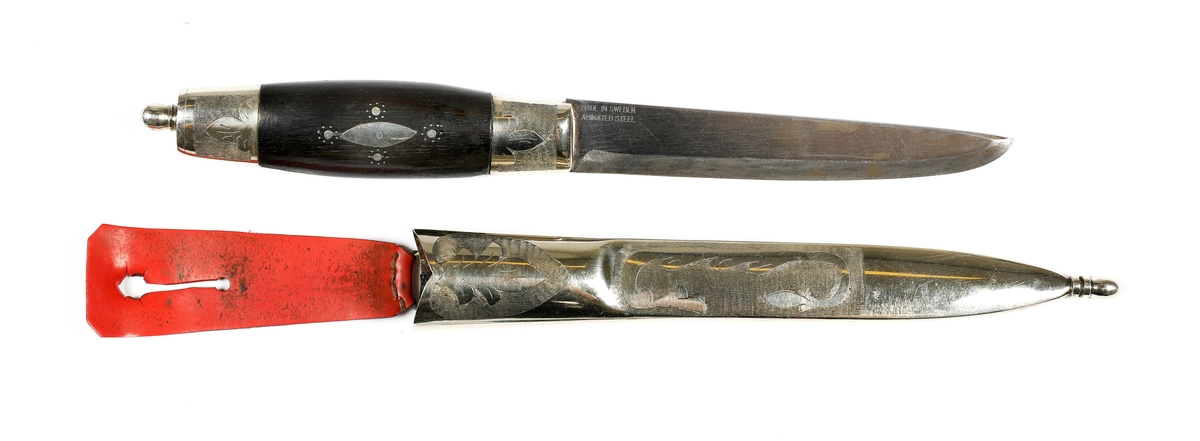 Kniv med slire i nysølv. 

Skaft med holker i nysølv. Endekule i nysølv. Skaft i ibenholt med innfelt dekor i nysølv.  Trambuleringsdekor på endeholker.  
Trambuleringsdekor på slire ( i skaftet).  Slire med  endeholker i nysølv, dekorert med trambuleringer. 
Hengslet hempe i kunstlær.
Bakside av slire påført teksten: H..H 
På knivskaftet står det: Made in Sweden. Laminated steel.