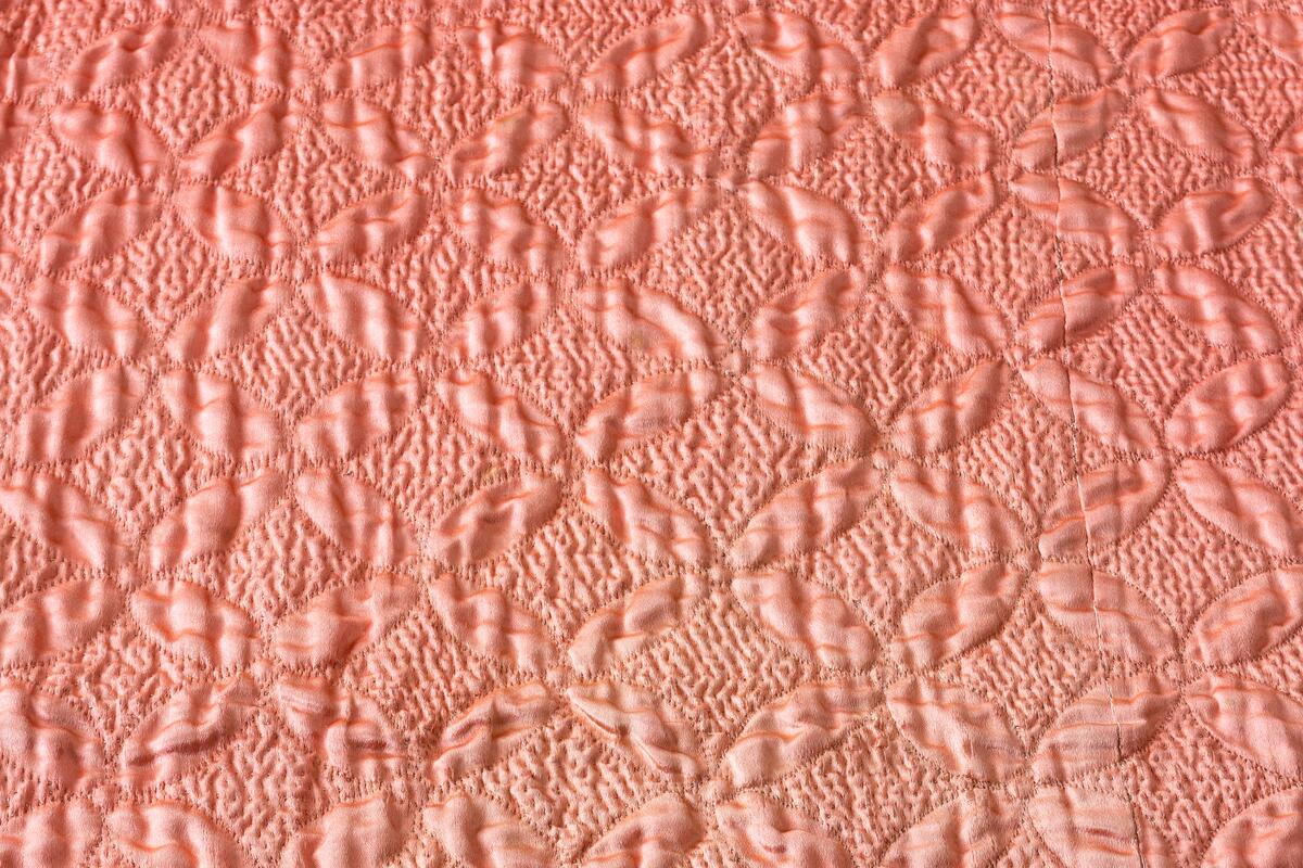 Av rosafärgad sidenatlas med foder av rosa bomullstyg, vadderat och stickat. Består av två broderade längder som ihopsytts. Stickningens mönster är fyra blad som bildar ett rutmönster över hela mittpartiet. Längs långsidorna en bård av flera nyanser i grått och vitt silke i schattérsöm, knutsöm, bottensömmar och stjälkstygn. L. 182 cm, B. 183 cm. Se även: C10594 och C11184 Denna typ av broderade sidentäcken från 1700-talets mitt och senare är ofta omsydda av s.k. "stubbar", vadderade kjolar, då dessa började komma ur bruk. Broderiet är mycket rikt och vittnar om stor skicklighet. Proveniens: Visbyköpmannen Jacob Lindström (1764-1818) hade i sina två äktenskap tre döttrar. När dessa gifte sig skänkte han dem förutom en präktig utstyrsel varsitt brudtäcke. Den andra dottern i ordningen, Anna Margaretha (1807-1891), gift med köpmannen och lantbrukaren Axel Hägg på Katthamra i Östergarn, fick detta täcke. Täcket har efter Anna Margaretha tillhört: 2) Dottern Maria Elisabeth Hägg (1837-1917), Katthamra. 3) Dottern Axelina Charlotta Jacobina (1843-1931), gift Sundell. 4) Axelinas dotter, Ester Kristina (f. 1882), gift Söderman, Katthammarsvik. År 1969 förvärvades det, genom flera sällskaps och fonders donationer, till Fornsalen. Täcket var under lång tid utställt på Fornsalen i utställningen "Gotland för 100 år sedan". Det visades i en dräktmonter tillsammans med de två andra brudtäckena från Jacob Lindströms döttrar. Läs mer: Ulla Melin, "Textila Släktklenoder: Några Anteckningar från Gotlands Hemslöjdsförenings Textilinventering 1944-1948", sid. 88-105, Gotländskt Arkiv 1948-49 & "Historien om tre brudtäcken", Utställningstext, Gotlands Museum
AV SIDEN, FODER AV ROSA BOMULLSTYG. VADDERAT OCH STICKAT. BESTÅR AV 2 BRODERADE LÄNGDER SOM HOPSYTTS. STICKNINGENS MÖNSTER ÄR 4 BLAD, SOM BILDAR ETT RUTMÖNSTER ÖVER HELA MITTPARTIET. LÄNGS LÅNGSIDORNA BÅRD AV FLERA NYANSER I GRÅTEIGT SILKE I SCHATTÉRSÖM, KNUTSÖM, BOTTENSÖMMAR OCH STJÄLKSTYGN. L. 182, BR. 183 CM. INKÖPT FRÅN FRU ESTER SÖDERMAN, KATTHAMMARSVIK,SE GOTL. ARKIV, 1948-49, SID 88.