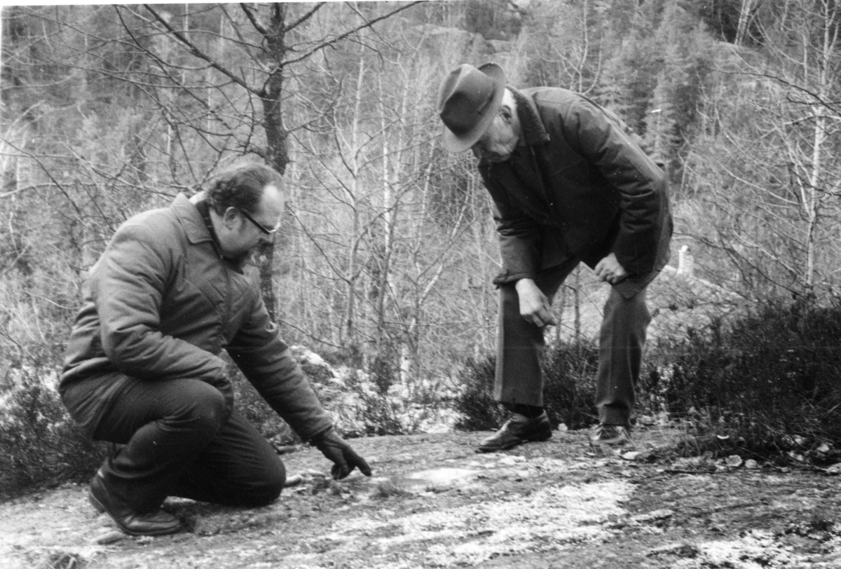 Bjørn Sandberg og Gunvald Braaten ved slipemerker i fjellet, Bråten  gård, Kjølebrønd. 
Bjørn Sandberg ser nøye på slipemerker fra bronsealderen (?) som Gunvald har påvist.
Gunvald og Bjørn i samtale i stua på Bråten.