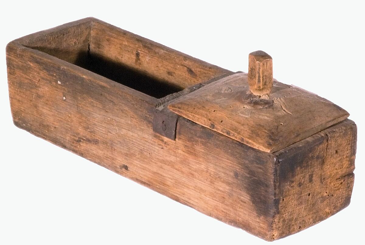Trälådan är utskuren ur ett enda trästycke med ett fack för eldstål (utan handtag), flinta och fnöske och ett fack för tändved.Någon tändved finns inte kvar, men däremot de andra föremålen, samt ett lock i trä med knopp. Ett brett järnbeslag tvärs över skiljeväggen finns också. Inga dekorationer eller inskriptioner är gjorda vilket gör den svår att datera. Den var säkert i bruk fram till att det blev vanligt att använda tändstickor på 1850-talet. Tekniken har däremot varit känd sedan vikingatiden så utan analys av materialen i sig så går det inte att göra en datering. I magasinet finns andra liknande askar eller skörlådor, bl a lådan med invnr C6554,   EM 2003 10 31