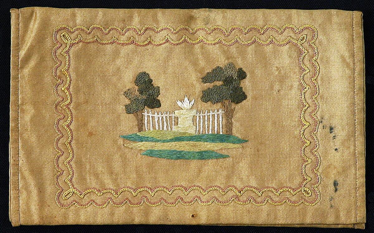 Sidenplånboken är av brungrönt tyg, modell bokomslag. Med broderier i flera färger både ut och invändigt, fodrad med rosa siden. På utsidan monogram "N R B"
På danska till L Ringbom och A C Mullde paa deras brullöpsdag 1766 i plånboksfodral af brunt sidentyg märkt N R B
